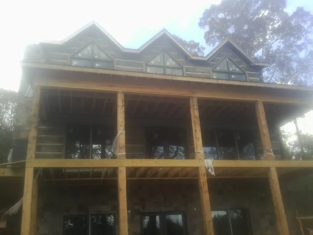 Dormers and porch framing on a large log home under construction — Roof Coating work by our crew in Bonaire