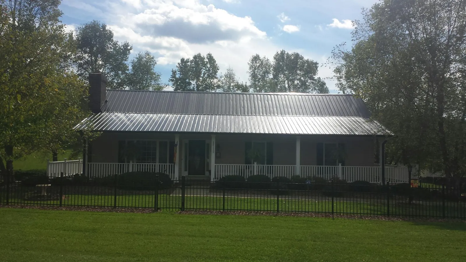 Gray metal roof on a brick ranch with a full width front porch — Gutter Guard Installation work by our crew in Bonaire