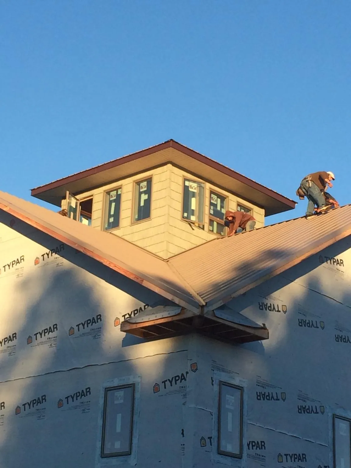 Roofers working around a rooftop cupola on a new metal roof at sunset — Roof Waterproofing in Bonaire by Roofing Brothers